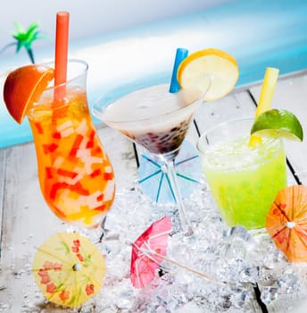 Three different colourful tropical fruit bubble tea sorts served chilled on a bed of crushed ice as a welcome refreshment at a beachfront resort