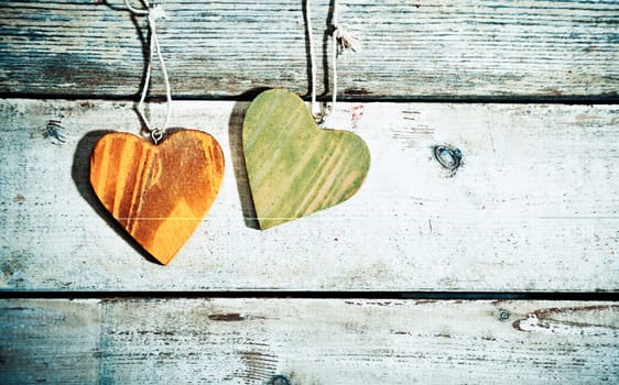 Rustic romantic hearts with a woodgrain finish hanging on old weathered timber planks with copyspace