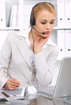 Blond business woman working in office, wearing headset