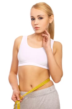 Sporty beautiful girl is measuring her waist on white