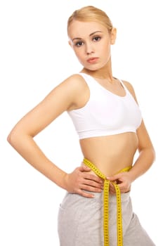 Sporty beautiful girl is measuring her waist on white