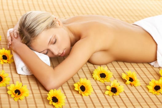 Portrait of Beautiful woman laying on bamboo mat around yellow flowers