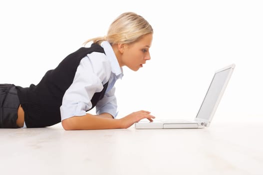 Businesswoman working on her laptop while lying down on the floor