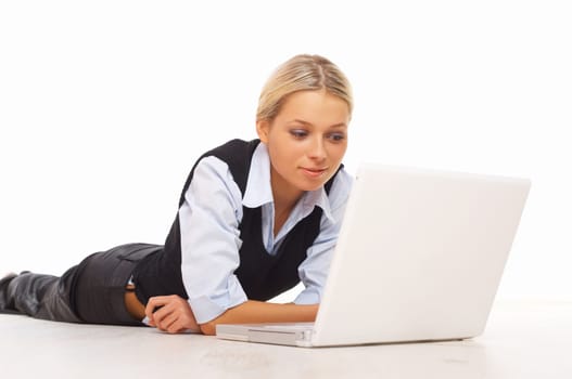 Businesswoman working on her laptop while lying down on the floor