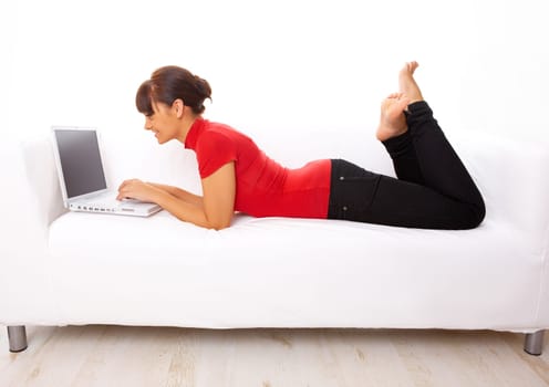 Young pretty women on white couch relaxing and using laptop computer