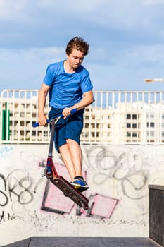 boy jumps with his scooter at the skate park