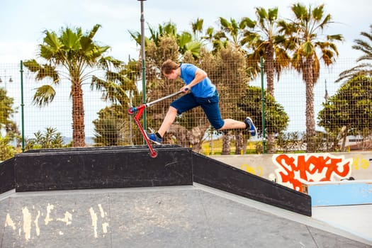 boy jumps with his scooter at the skate park