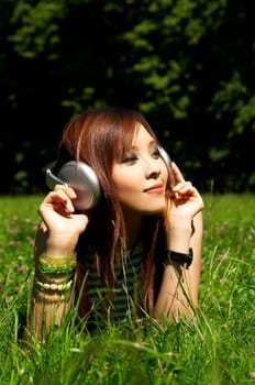 Beautiful asian young girl with headphones, listen to music on meadow