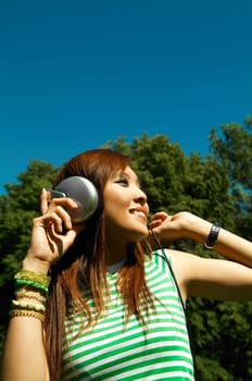 Beautiful asian young girl with headphones, listen to music on meadow