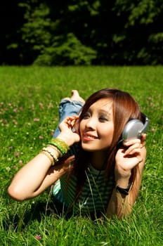 Beautiful asian young girl with headphones, listen to music on meadow