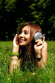 Beautiful asian young girl with headphones, listen to music on meadow