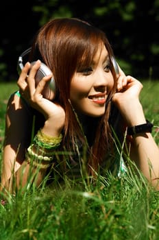 Beautiful asian young girl with headphones, listen to music on meadow