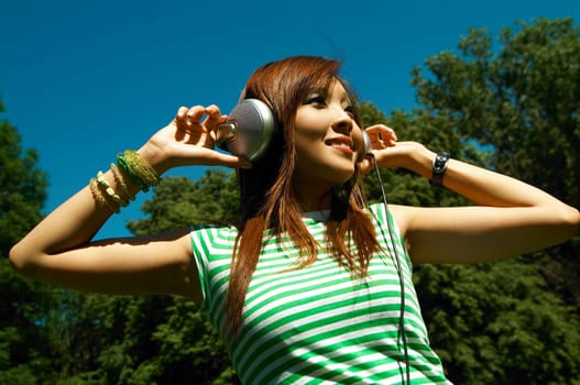 Beautiful asian young girl with headphones, listen to music on meadow