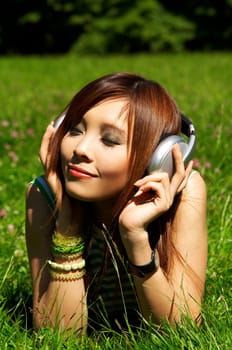 Beautiful asian young girl with headphones, listen to music on meadow