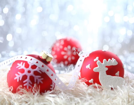 Red Christmas decorations on white material with a sparkling bokeh of silvery festive lights