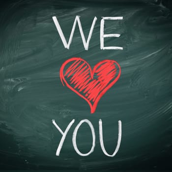 We Love You. Handwriiten message in chalk on a blackboard incorporating a red heart symbol for love.