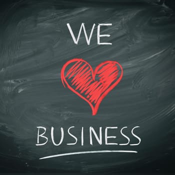 We Love Business. Handwriiten message in chalk on a blackboard incorporating a red heart symbol for love.