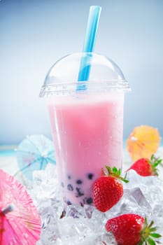 Fruity Strawberry Boba Bubble Tea on crushed ice, standing on a deck near the beach