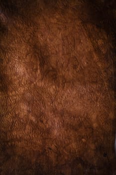 Abstract background of dark brown leather with a central highlight, shadows and strong texture