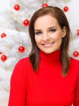 Beautiful woman next to christmas tree wearing red sweater