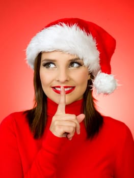 Portrait of beautiful woman wearing santa claus hat on red background