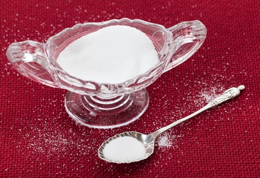 Table salt crystals in cut glass bowl on red tablecloth