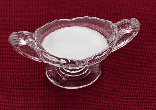 Table salt crystals in cut glass bowl on red tablecloth