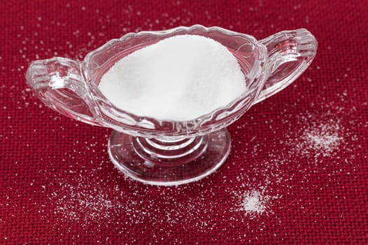 Table salt crystals in cut glass bowl on red tablecloth