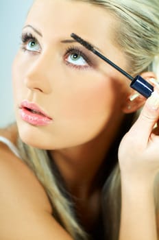 Portrait of blonde young sexy woman doing makeup