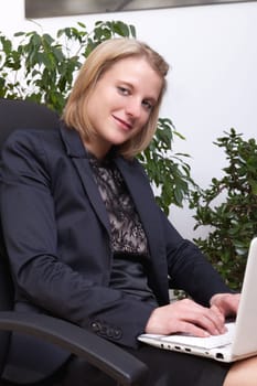 Young elegant businesswoman sitting with a white netbook on her kien