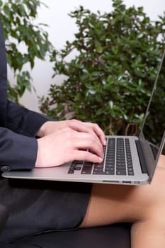 Young businesswoman with a notebook on her knees working on