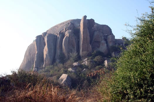 Huge rock with human-shaped rocky figurines in the front