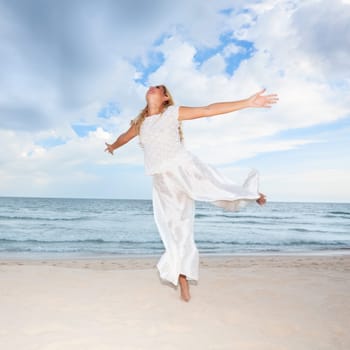 Young woman in white dancing on the beach