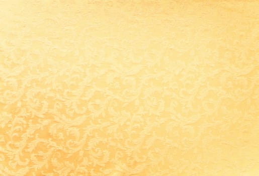 Abstract background of a heavy golden brocade fabric with interwoven repeat design.