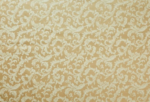 Abstract background of a heavy beige brocade fabric with interwoven repeat design.