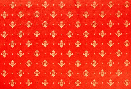 Abstract background of a heavy red brocade fabric with interwoven repeat design.