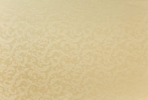 Abstract background of a heavy beige brocade fabric with interwoven repeat design.