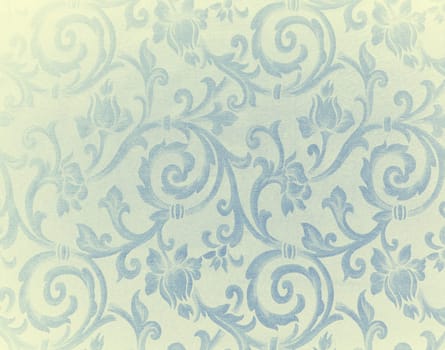 Abstract background of a heavy light yellow and blue brocade fabric with interwoven repeat design.