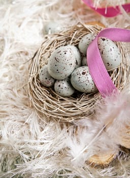 Speckled blue Easter Eggs in a nest on feathers and a pink ribbon