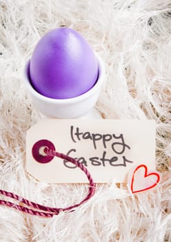 Purple egg in an egg cup with a Happy Easter tag