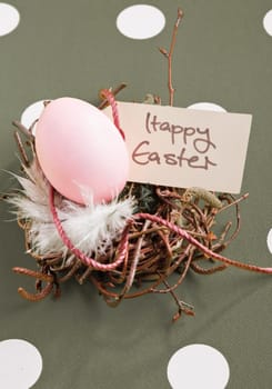 Colored egg in a small nest with a Happy Easter tag