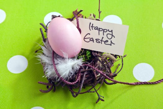 Colored egg in a small nest with a Happy Easter tag