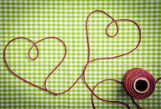 Hearts drawn with purple thread through a tag over a checkered fabric pattern
