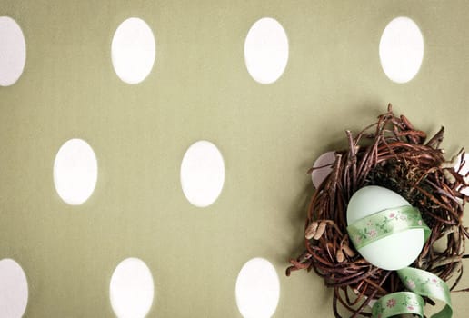 Small nest containing colored egg over a Easter concept background, with a bow
