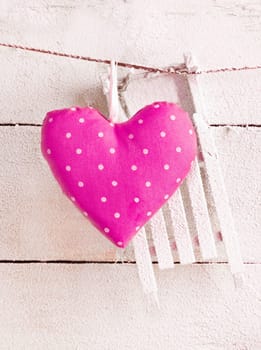 Romantic checked pink needlework heart for Valentines hanging on snow white boards with copyspace