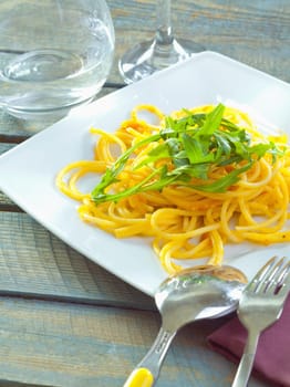 Plate of delicious pasta topped with fresh herbs served ready for dining.
