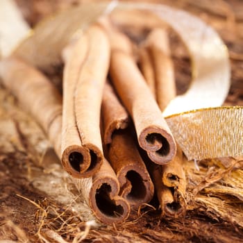 a few cinnamon sticks on wooden background an a golden bow