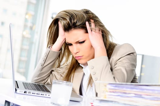 young woman stressed at work, taking an aspirin cahet