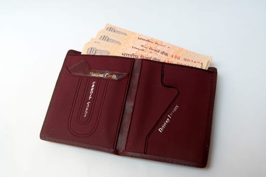 Brown wallet containing Indian currency notes isolated on white