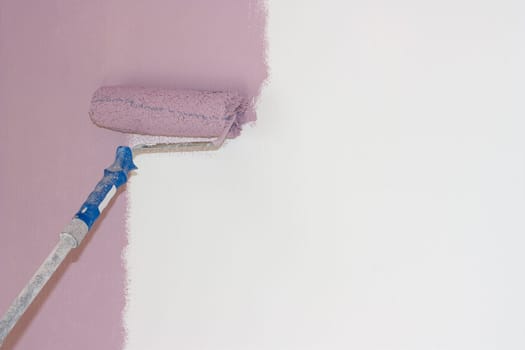 A roller with a pink color on the white wall.